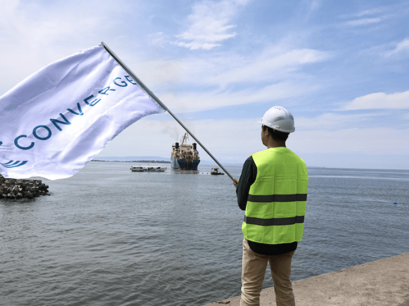 A Converge team member raises the company flag in Davao to mark the activation of the Bifrost subsea cable, the Philippines’ first direct link to the United States./Photo from Converge