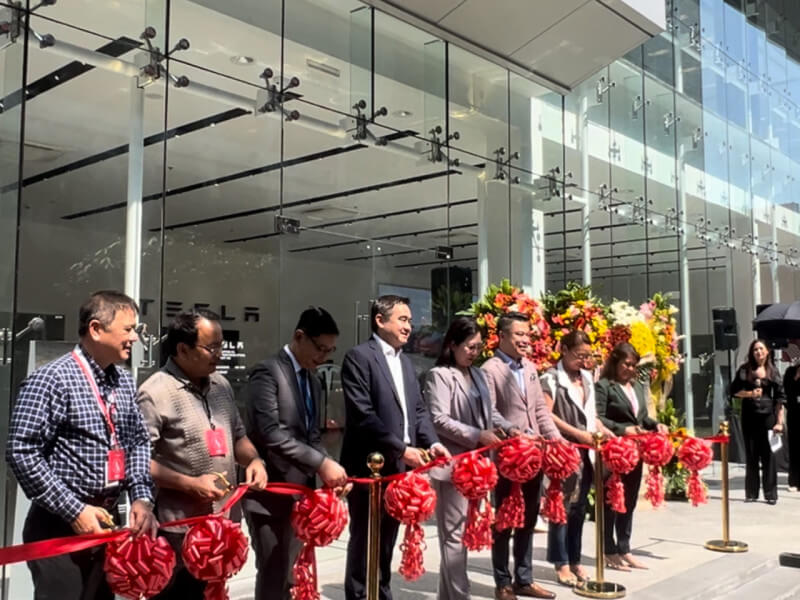Secretary Frederick Go (center in a black blazer) joins the ribbon-cutting ceremony to inaugurate the Tesla Experience Center./Photo by Miguel R. Camus 