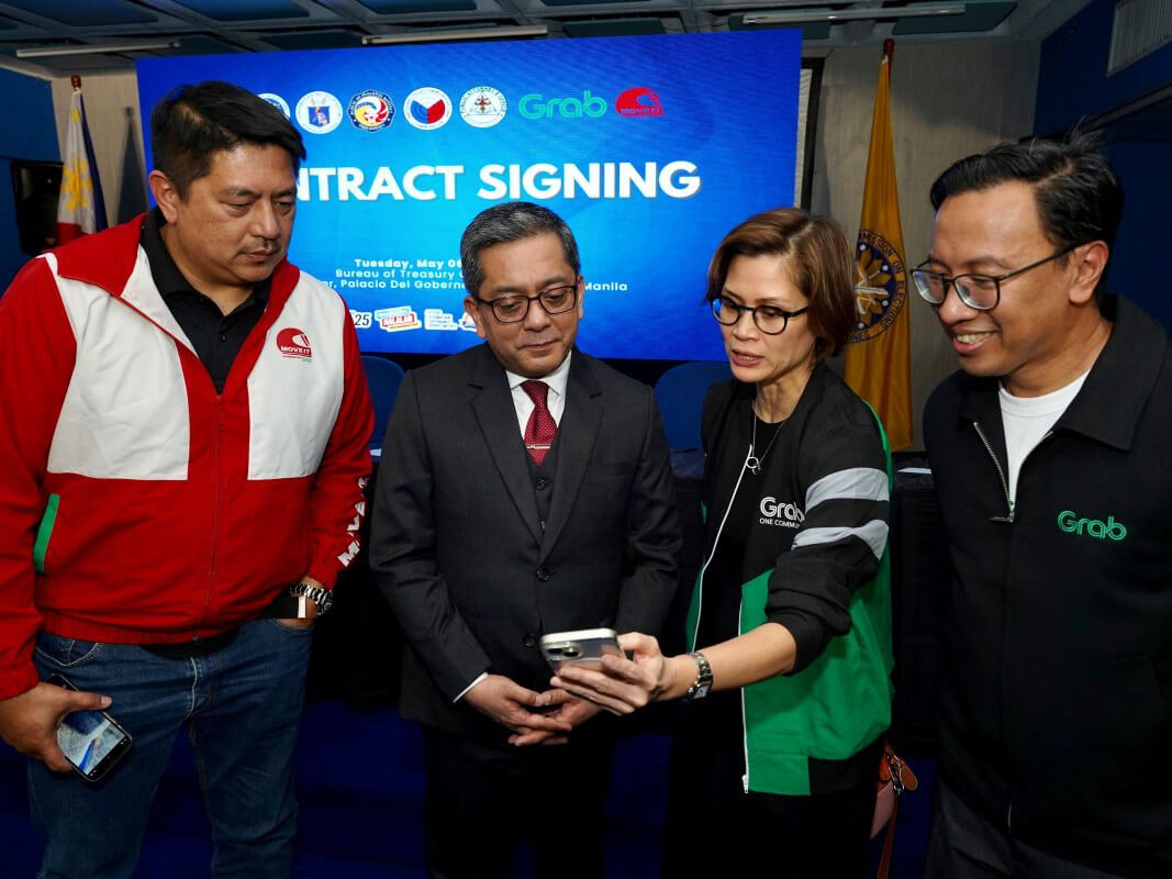 Move It GM Wayne Jacinto, Grab Philippines head of public affairs Sherielysse Bonifacio and Grab Philippines country head Ronald Roda demonstrate to Comelec Chair George Erwin Garcia how Grab users can access election reminders as part of the platform’s #RideToVote campaign./ Photo from Grab Philippines.  