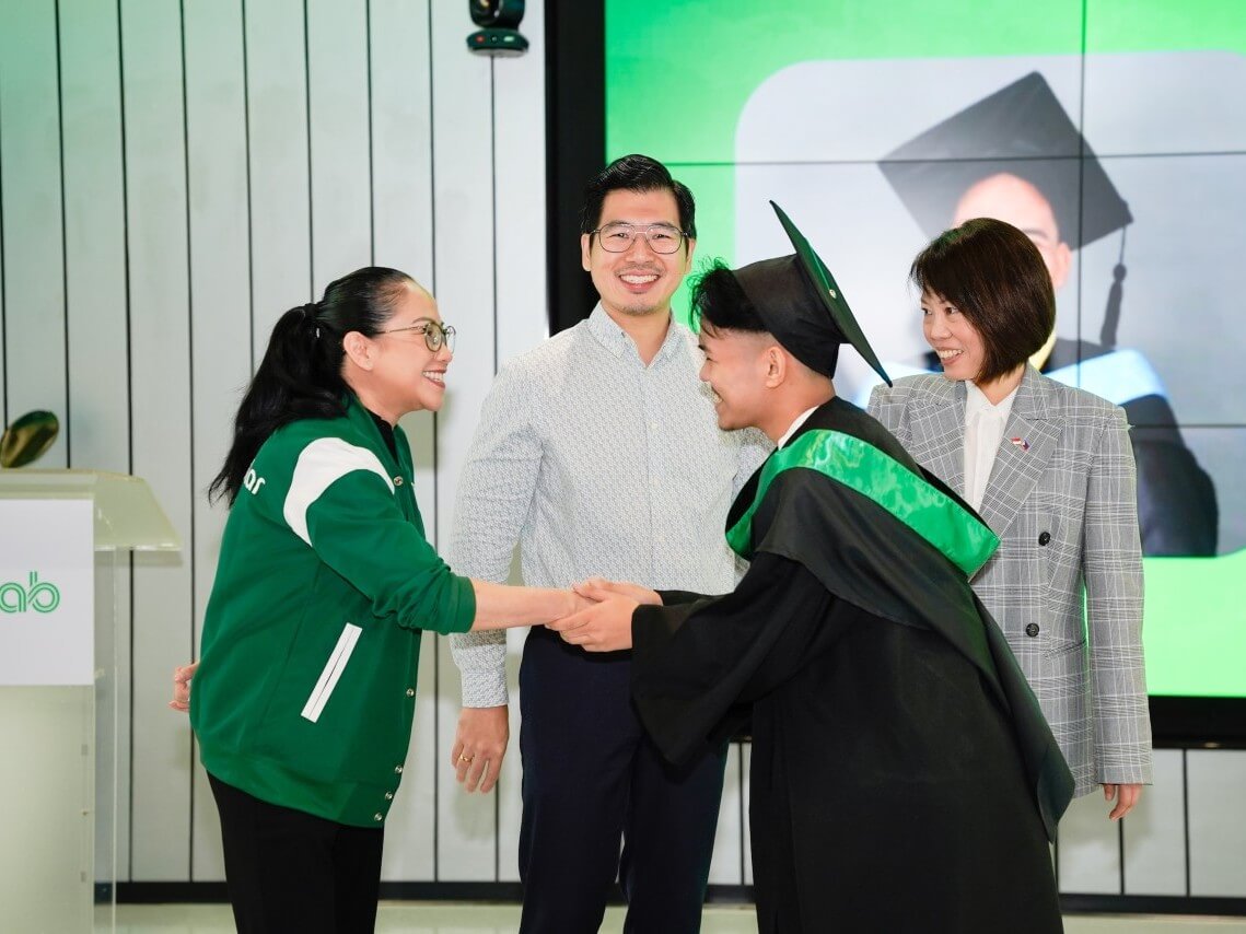Grab Financial Group Philippines president CJ Lacsican congratulates GrabScholar graduate John Lloyd Villa alongside DepEd Undersecretary Edson Sy and Singapore Ambassador to the Philippines Constance See. | Contributed photo