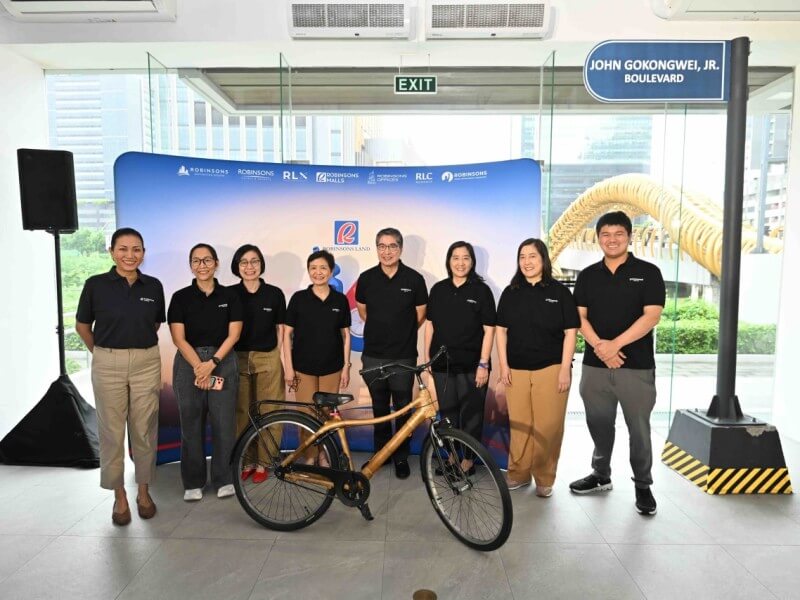Gokongwei family members and executives gather around a bicycle, symbolizing the humble beginnings and entrepreneurial journey of taipan John Gokongwei Jr./Photo from RLC&nbsp;