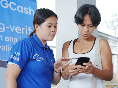 Mutya (right) sets up her GCash account with help from a staff member (left) after completing her National ID registration. | Contributed ​photo