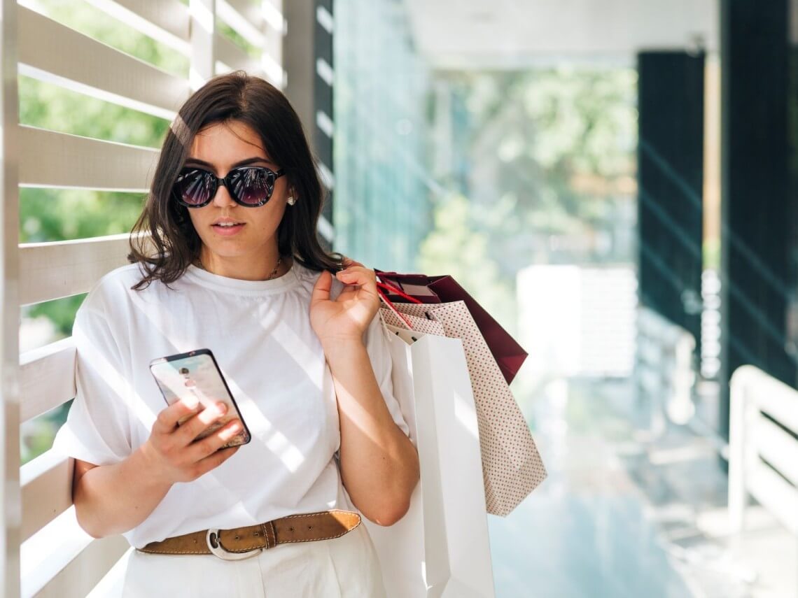 A shopper checks messages on her smartphone while carrying retail purchases, reflecting the growing role of messaging platforms in product discovery, customer engagement, and online shopping, according to Rakuten Viber. | Contributed photo