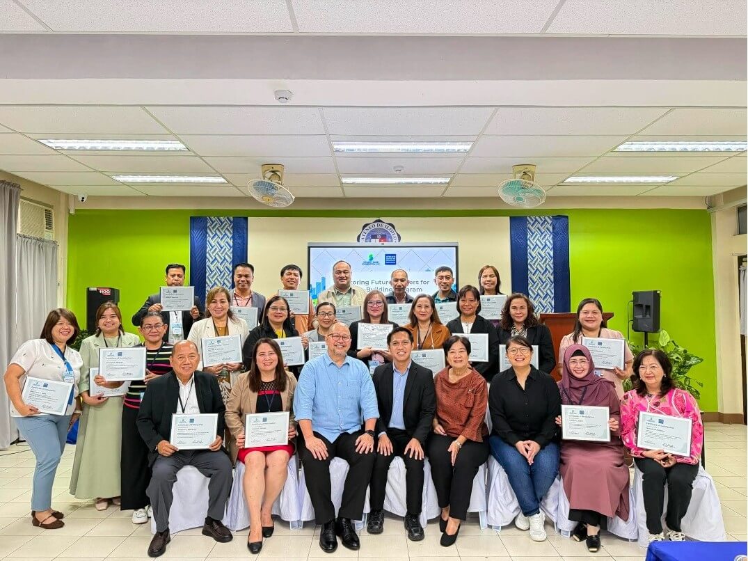 Public school principals receive certificates after a five-day community engagement training in Iloilo. Joining them are DepEd NEAP director Dr. Joseph Dela Cruz (third from left), SBFI executive director Louie De Real (fourth), SBFI trustee Melissa Aquino (fifth), and ACED officer-in-charge Amelia P. Dycoco (sixth). | Contributed photo